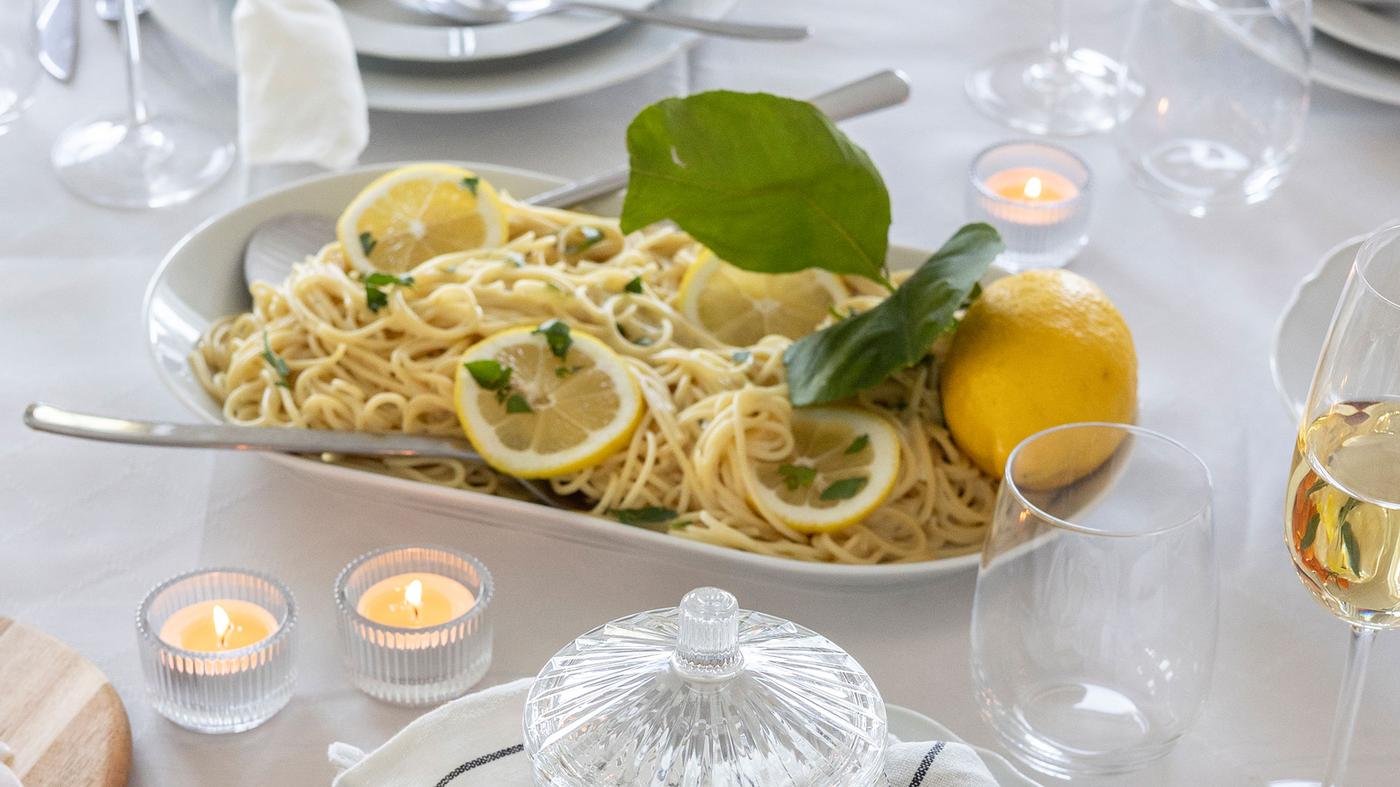 In der Mitte des Tisches steht ein Teller mit Zitronenpasta.