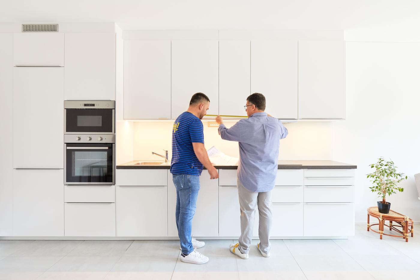 In einer weissen IKEA Küche in einer Neubauwohnung steht ein IKEA Mitarbeiter und unterhält sich mit dem Besitzer der Überbauung.