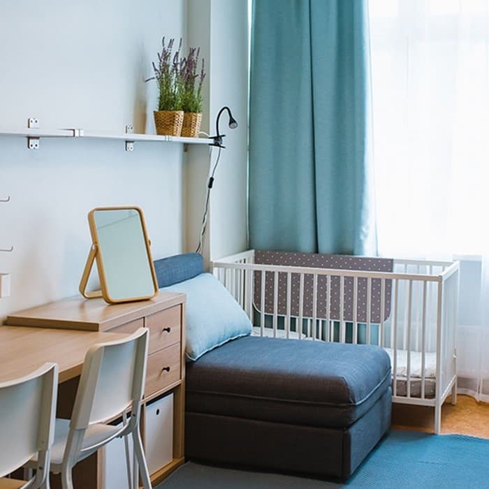 In the family room, there is a desk, a KALLAX shelving unit, a fold-out armchair and a children’s bed.