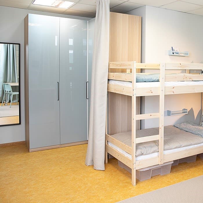 In the family room, there is a wooden bunk bed and a corner PAX wardrobe with blue-grey doors.
