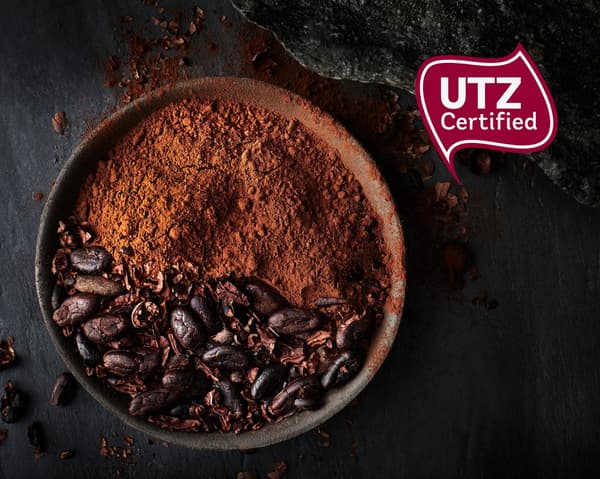 إناء مملوءة بحبوب الكاكاو المعتمدة من UTZ، معظمها تم طحنه على شكل مسحوق شوكولاتة، مع شعار UTZ.