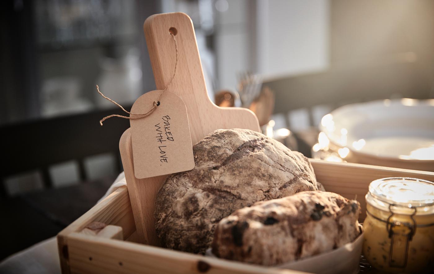 Individueller Geschenkkorb in einer KNAGGLAG Kiste mit frischem Brot, einem Schneidebrett und Aufstrichen in Gläsern.