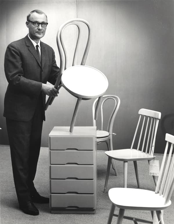 Ingvar Kamprad en el inicio de su empresa IKEA, mostrando productos icónicos como las sillas escandinavas clásicas y veladores también del mismo estilo de diseño. Foto en blanco y negro.