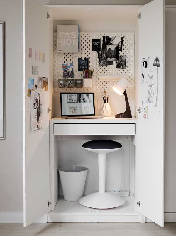 Inside a KLEPPSTAD wardrobe, a MICKE desk, a NILSERIK standing support, a lamp and a pegboard form a very compact workspace.