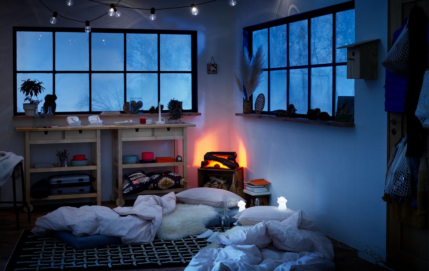 Intérieur de type maisonnette en période hivernale, matelas sur le sol comme lits temporaires, veilleuses LED à côté. 