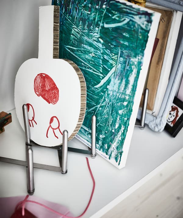 Intérieur d’une armoire de cuisine, où un range-couvercles maintient une série de dessins et d’œuvres d’enfant.