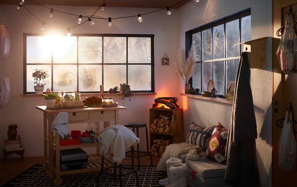 Interior of a small, cabin-like space. Wintery landscape hinted through windows, turkey dinner buffet and fireplace inside.