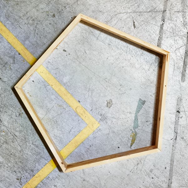 إطار خشبي على شكل خماسي أضلاع على أرضية خرسانية بها خدوش.