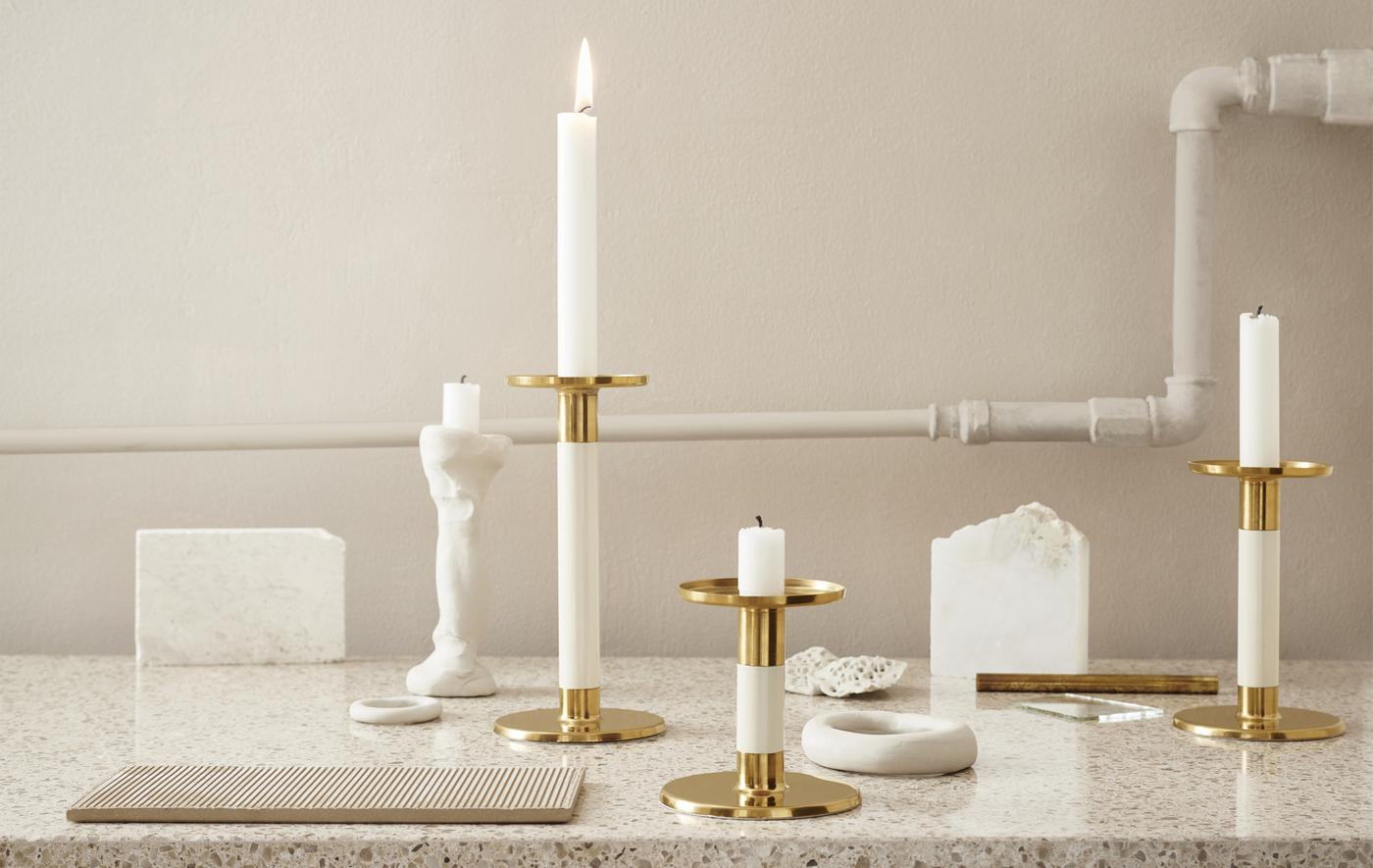 Ivory and gold-coloured candlesticks displayed on a marble worktop.