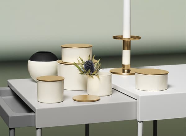 Ivory, black and gold-coloured boxes, vases and candlestick displayed on a nest of tables.
