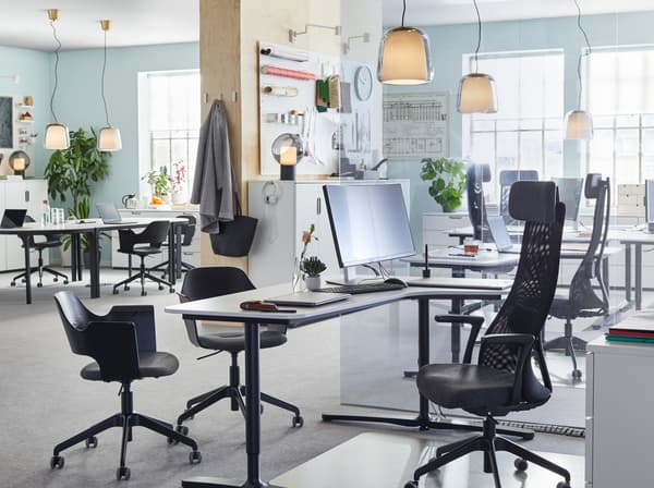 JÄRVFJÄLLET adjustable black work chairs and smooth BEKANT white sit-stand desks arranged in an open and airy office space.