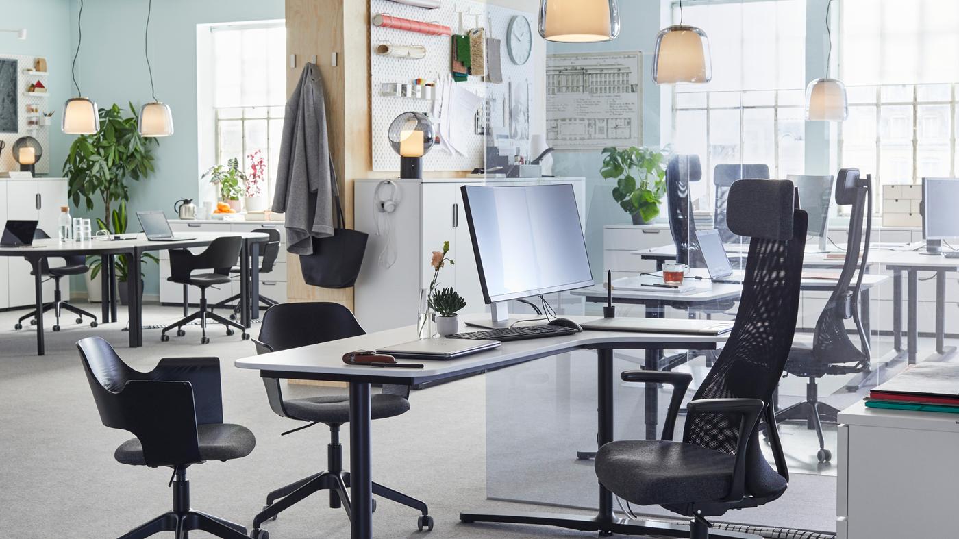 JÄRVFJÄLLET adjustable black work chairs and smooth white sit-stand desks arranged in an open and airy office space.