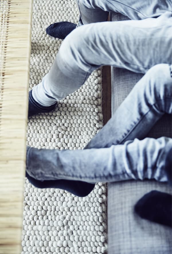 Jambes qui pendent au bord du canapé et table basse.