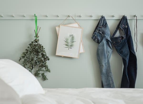 Jeans, plantes séchées et œuvres d’art accrochés à des patères KUBBIS peintes dans la même couleur que le mur de la chambre à coucher.