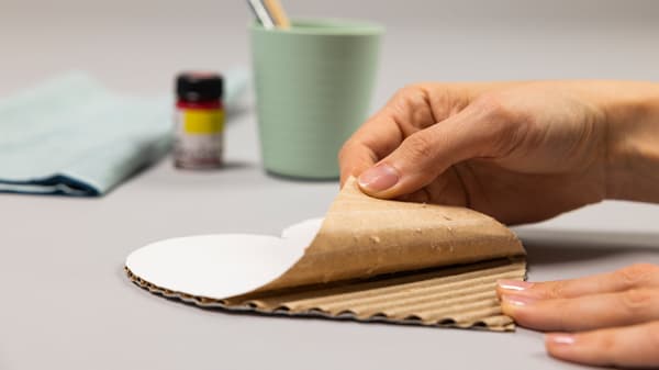Jemand schneidet entlang der Vorlage den Karton mit einem Cutter aus.