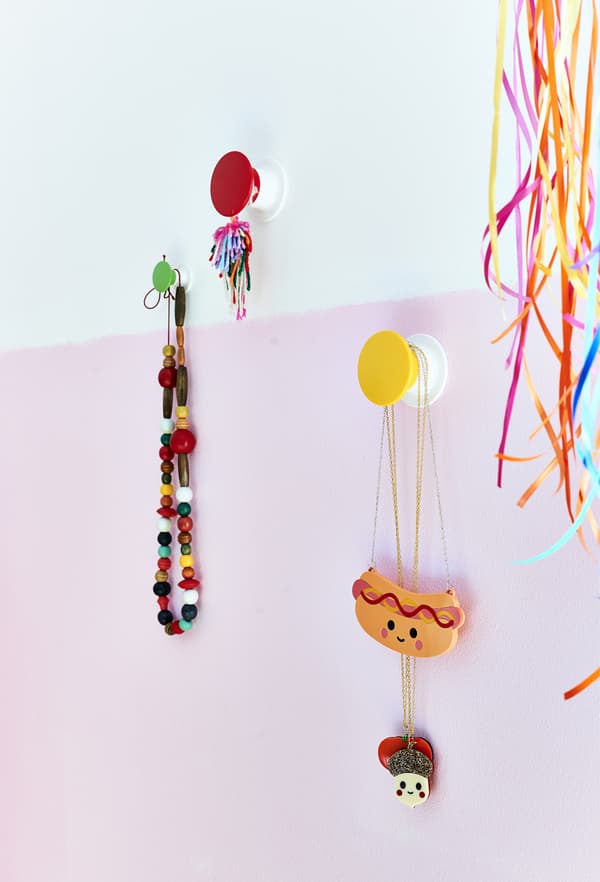 Jewellery on colourful wall hooks.