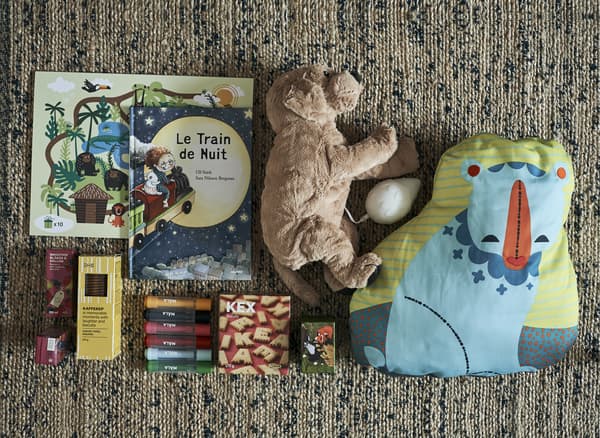Jouets, livres et collations disposés sur un tapis.