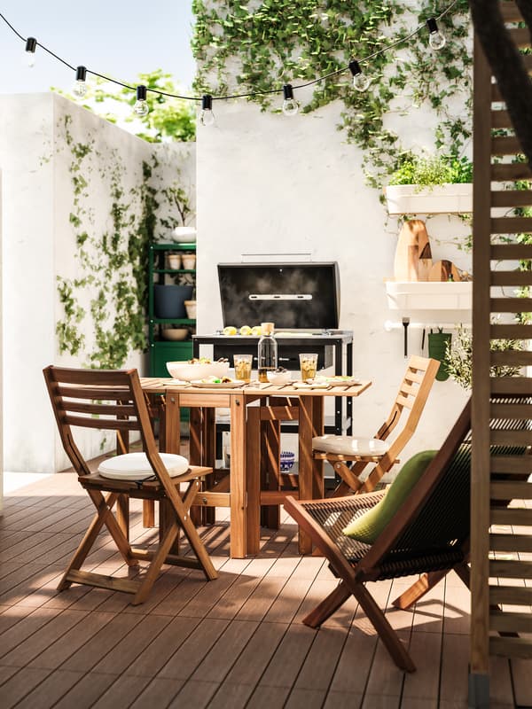 Juego de terraza pequeño de madera en frente de una parrilla.