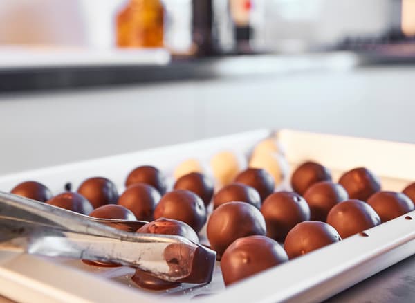 Just-made chocolate truffles sit on a white serving tray.