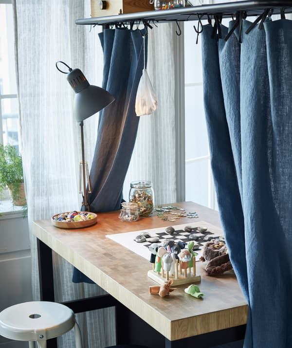جزيرة مطبخ مع ستائر زرقاء ولوحة لعب ومرطبانات موضوعة على سطح العمل.