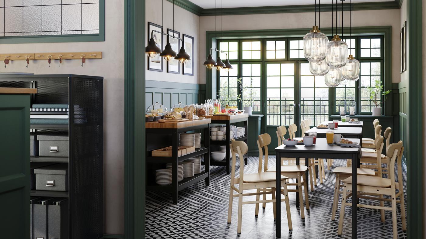 Kafić sa zelenim zidnim panelima i TOMMARYD stolovima, RÖNNINGE stolicama od brezovine i dva VADHOLMA kuhinjska ostrva.