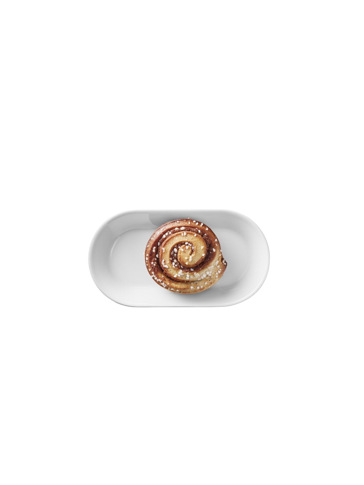 Kaneelbroodje met suikerafwerking, geserveerd op een wit ovaal schaaltje.
