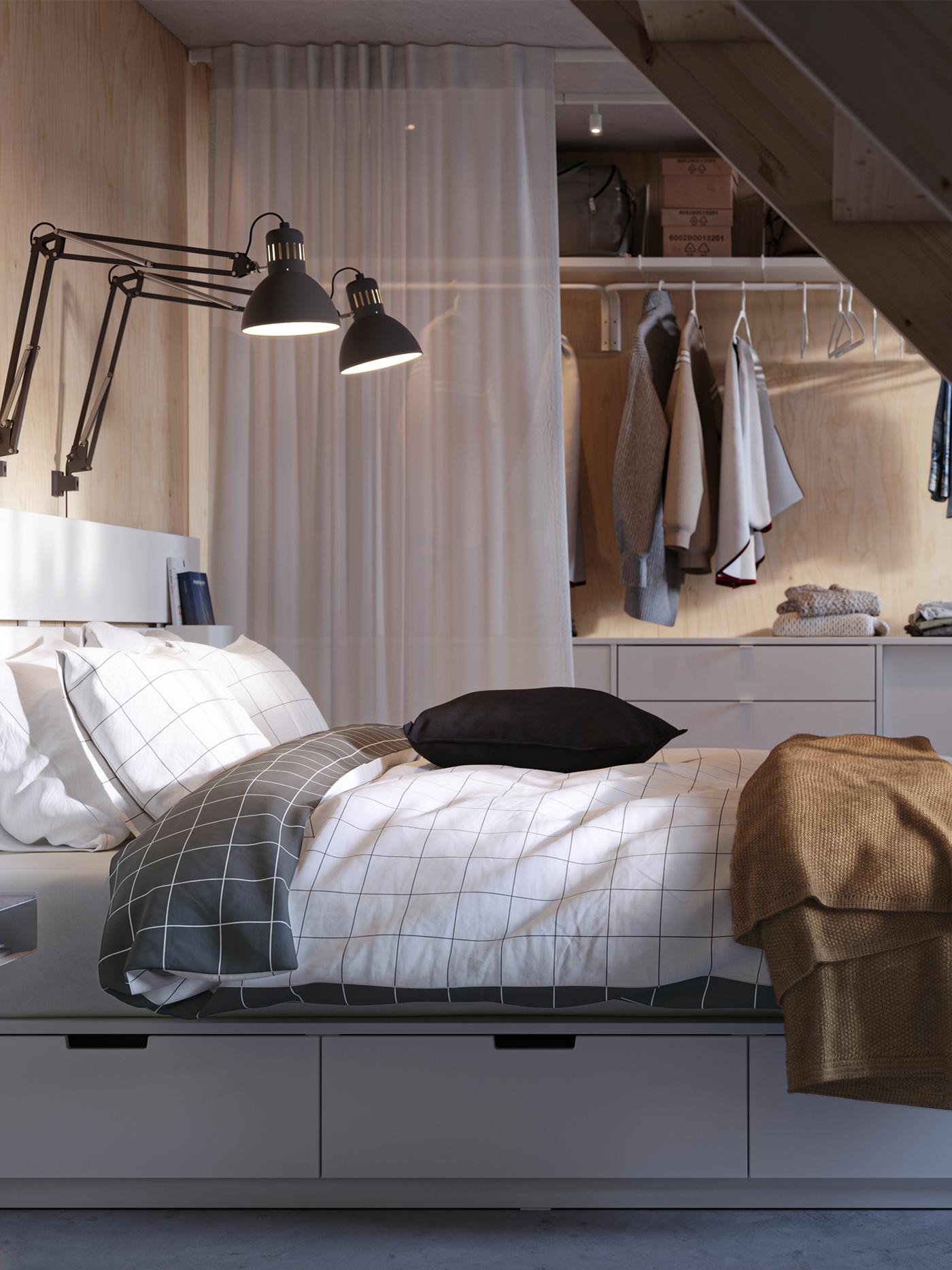 Katil dengan storan dan kepala katil NORDLI berwarna putih yang ditutupi dengan linen katil VITKLÖVER, di hadapan kombinasi storan ELVARLI.