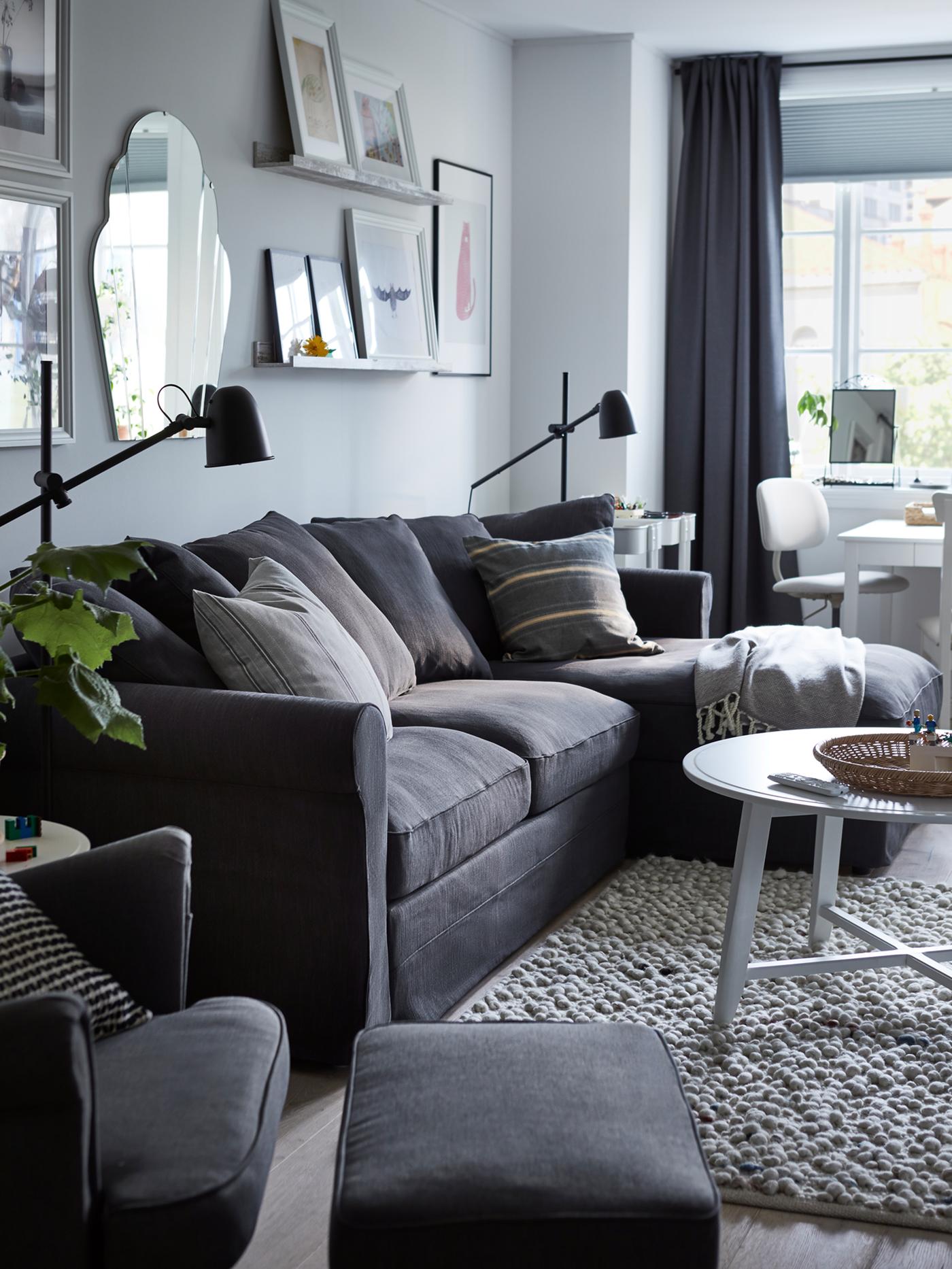 Katil sofa 3 tempat duduk dengan chaise longue GRÖNLID berwarna kelabu di ruang tamu dengan meja kopi bulat berwarna putih terletak di atas ambal di hadapannya.