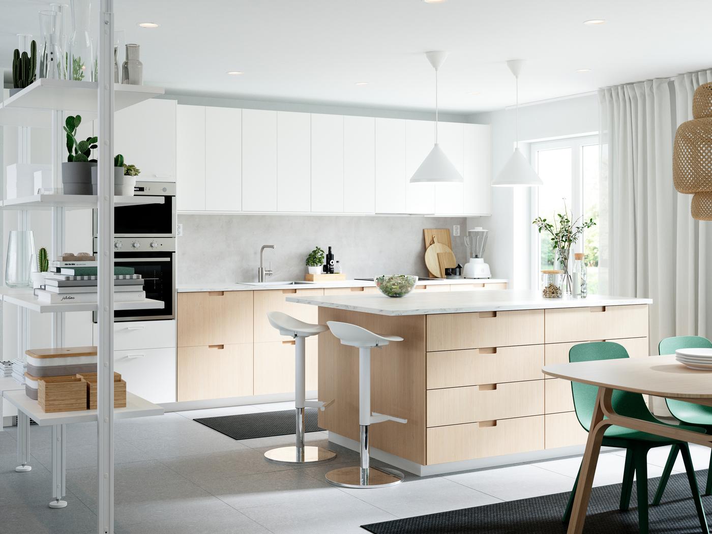 Keuken met EKBACKEN laminaatwerkbladen in wit marmerpatroon, groene stoelen en verschillende keukentoestellen.