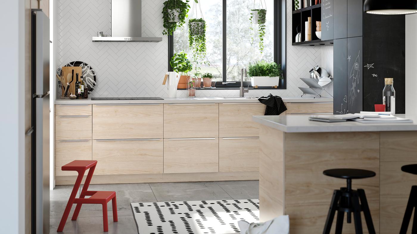 Kitchen cabinets with ASKERSUND doors in light ash wood-effect and cabinets with anthracite blackboard surface doors.