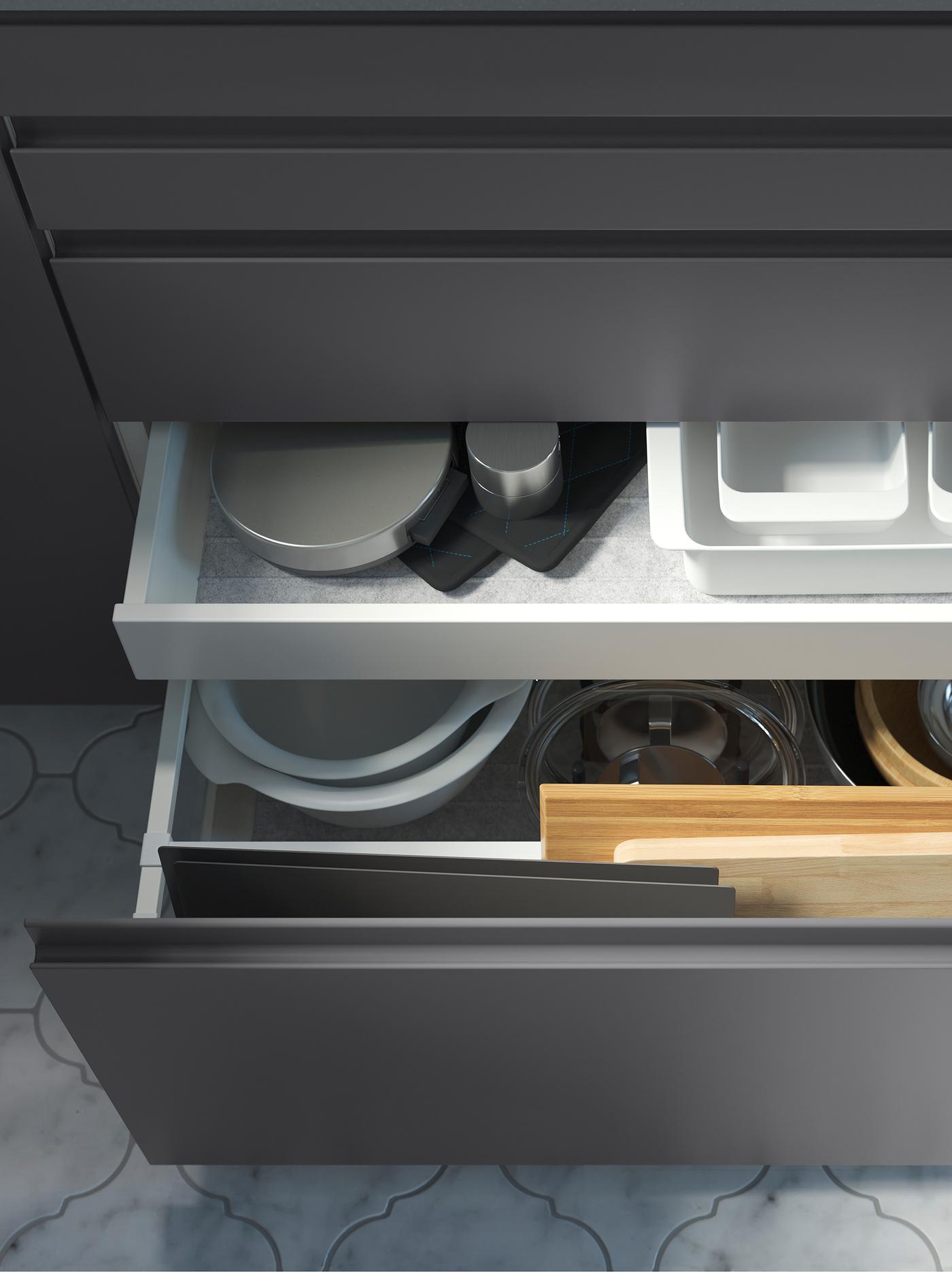 Kitchen cabinets with dark-grey drawer fronts. One drawer is open showing another drawer inside, both storing cookware.