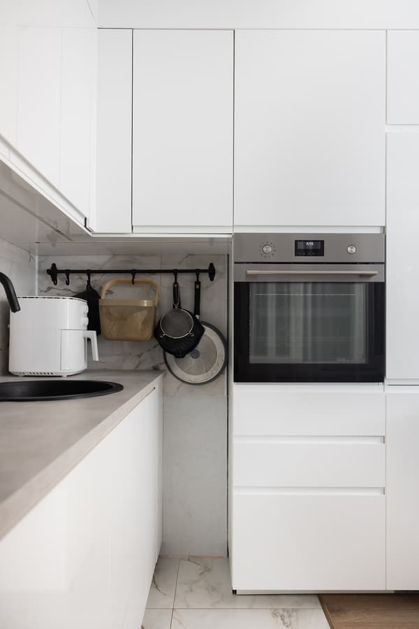 Kitchen corner with tall cabinets and a built-in oven; closed cupboards and a tidy worktop are visible.