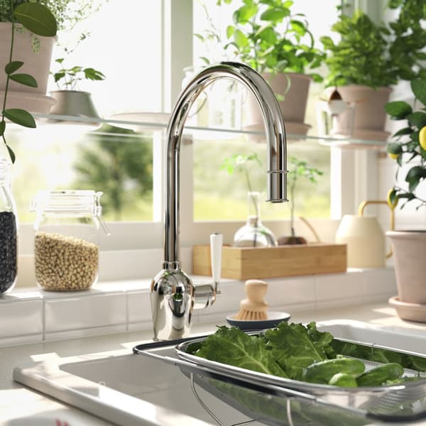 Kitchen sink with a water tap and draining board filled with fresh vegetables.				