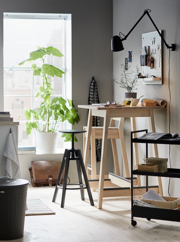 Kitchen where a NORRÅKER bar table serves as a workspace with a DALFRED bar stool and a trolley with related accessories.