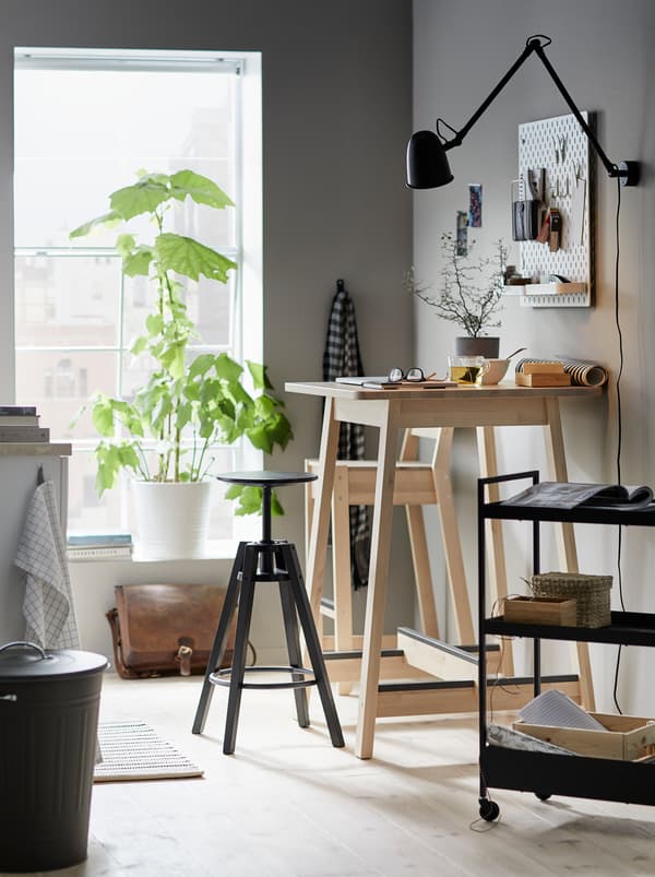 Kitchen where a NORRÅKER bar table serves as a workspace with a DALFRED bar stool and a trolley with related accessories.