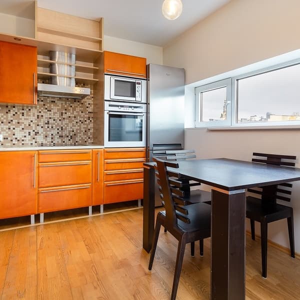 Kitchen with wooden cabinets, mosaic backsplash, and dining table.
