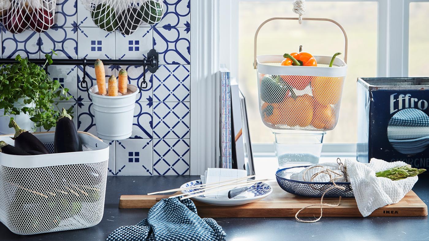Kitchen worktop with various produce kept in hanging and standing baskets, like KUNGSFORS nets and RISATORP baskets.