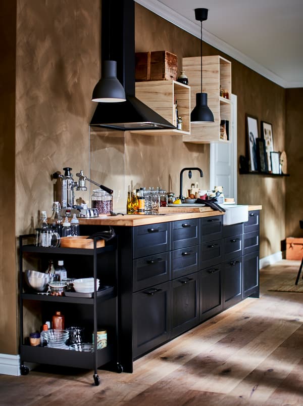 Kitchenette bien équipée avec petits éléments muraux ouverts, hotte et faces de tiroir LERHYTTAN foncées.