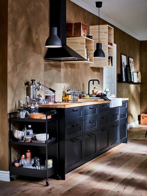 Kitchenette bien équipée avec petits éléments muraux ouverts, hotte et faces de tiroir LERHYTTAN foncées.