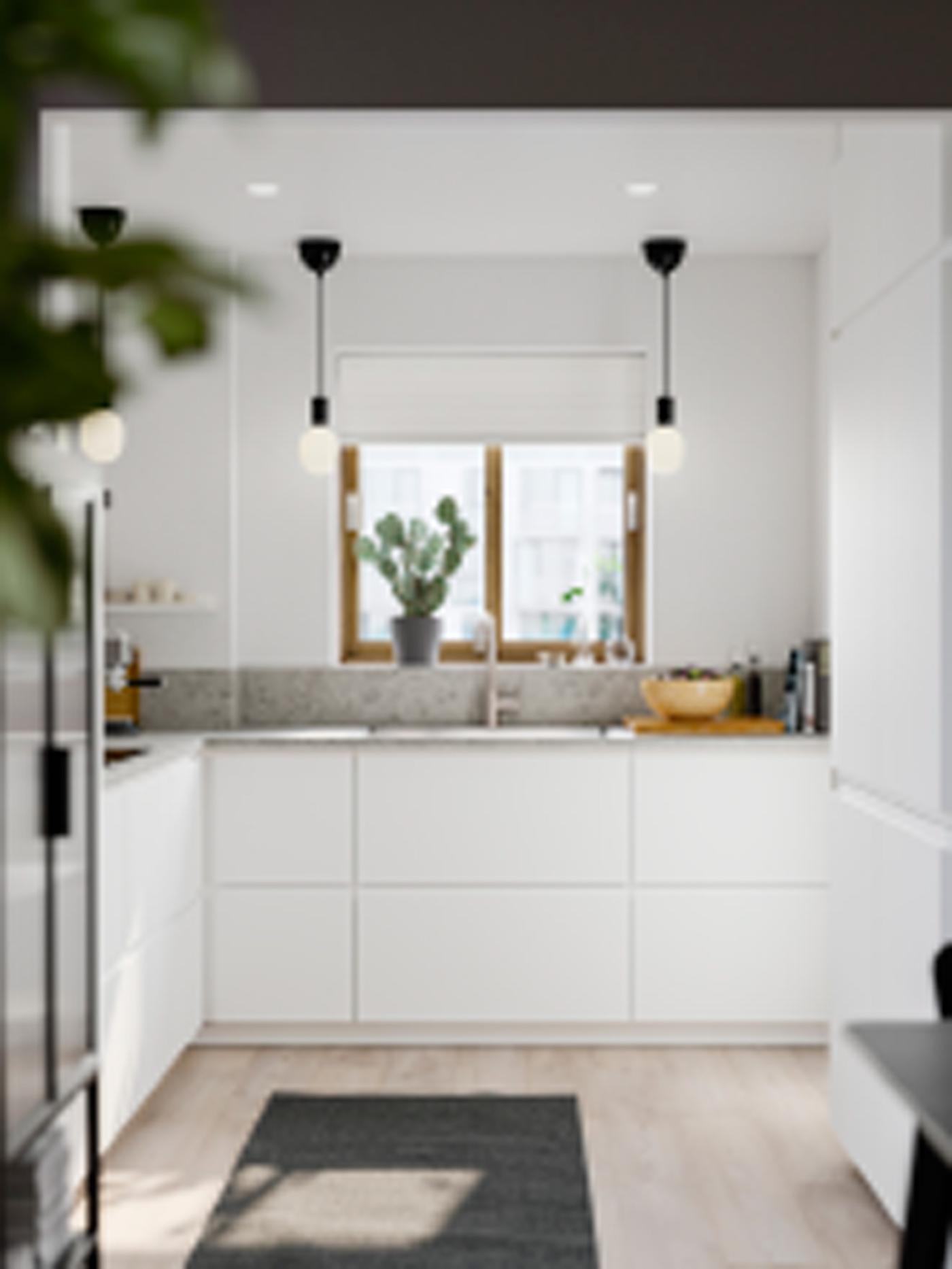 Kleine heldere keuken met matwitte VOXTORP fronten, witte wanden, een grijs vloerkleed en kleine zwarte hanglampen.