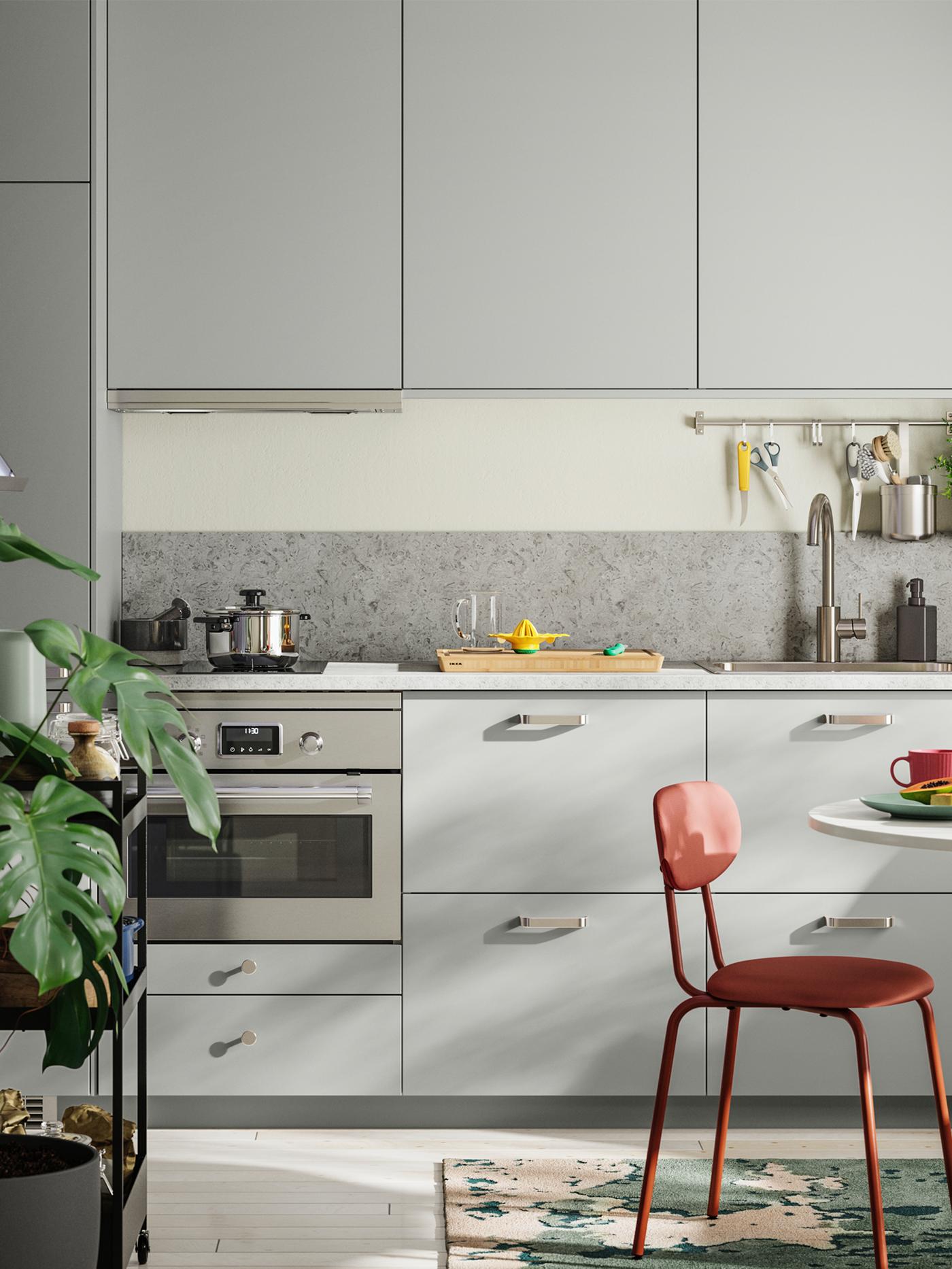 Kleine keuken op één lijn met lichtgrijze HAVSTORP fronten bij een kleine eetruimte en groene planten.