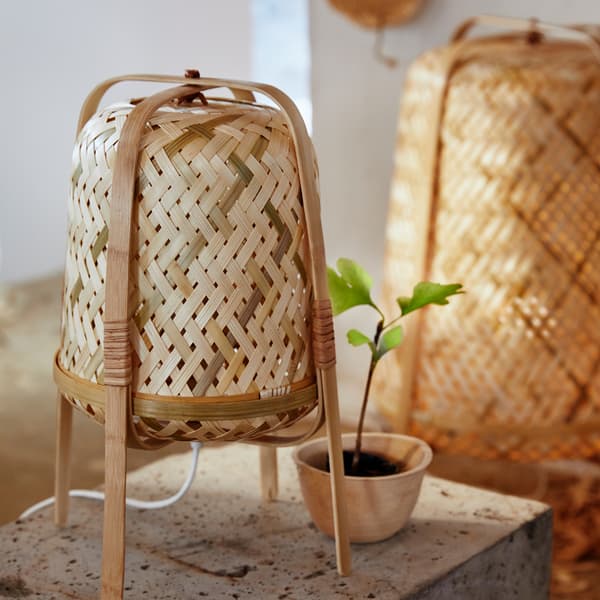 KNIXHULT small table lamp woven from bamboo, with the matching KNIXHULT floor lamp in the background.