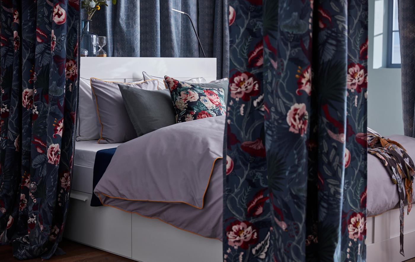 Krevet je uokviren uz nekoliko zavesa od tamnoplave IKEA FILODENDRON tkanine cvetnih šara.
