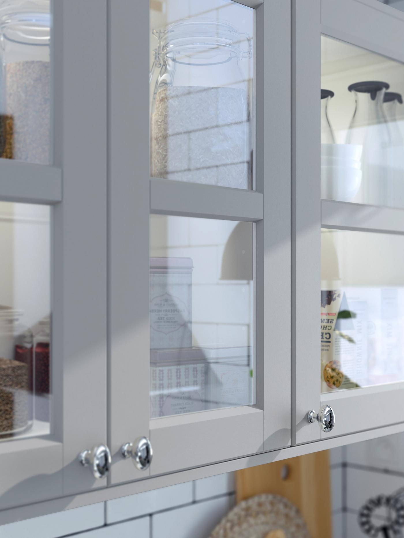 Küchenschränke mit LERHYTTAN Türen mit gehärtetem Glas und hellgrauen Rahmen.