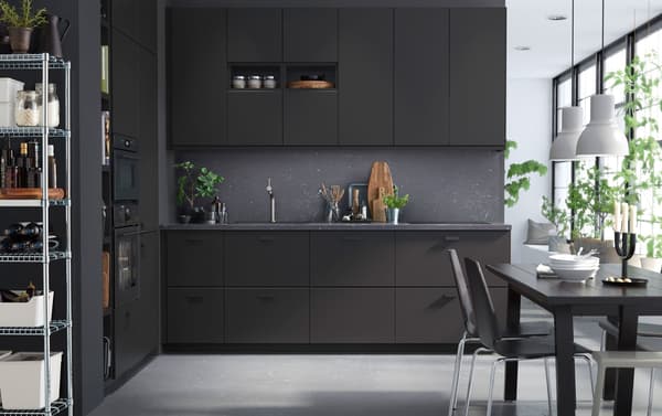 KUNGSBACKA kitchen with anthracite units, and dark grey walls and dining table. Light comes in from a big window.