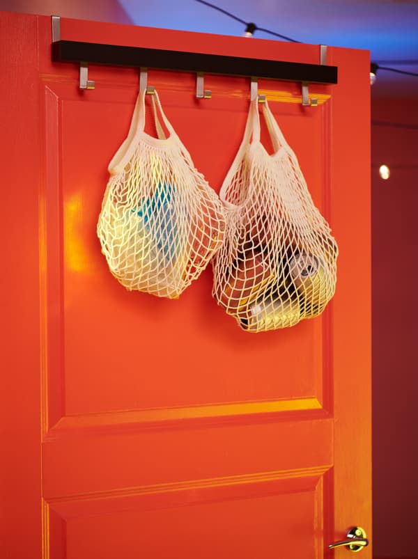 KUNGSFORS net bags filled with empty cans and similar disposables, hooked to a TJUSIG hanger at the top of a door.