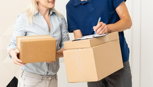 Kvinna som tar emot ett paket från utlämningsställe.