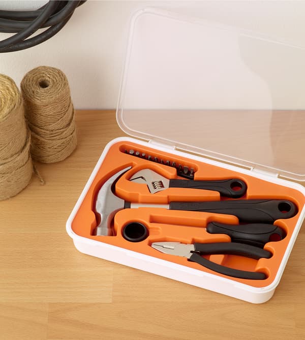 La boîte à outils FIXA remplie de différents outils posée sur une surface en bois.