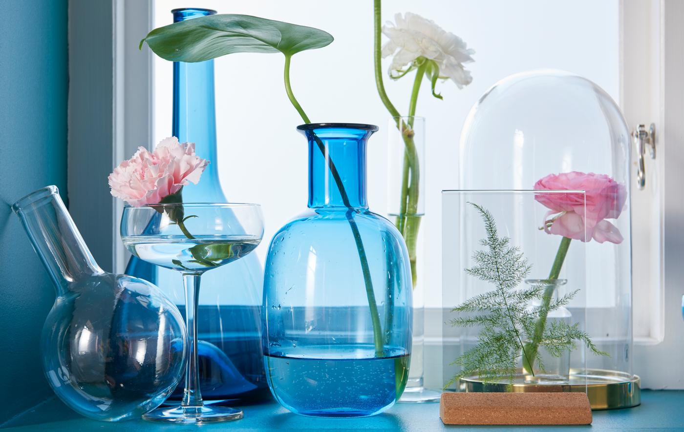 La cloche en verre BEGÅVNING de chez IKEA a un socle en acier métallisé couleur laiton. Elle permet d’exposer vos objets préférés tout en les protégeant de la poussière. Pour décorer la fenêtre, nous y avons placé une fleur naturelle, avec d’autres vases en verre transparent à côté.