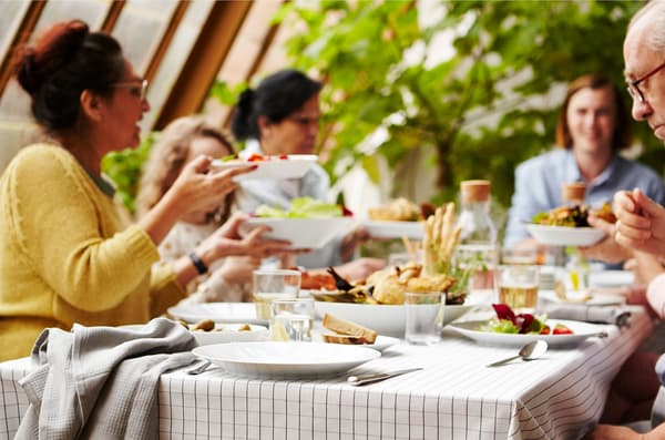 La famille et les amis réunis autour d’une table dressée avec la vaisselle blanche IKEA 365+.